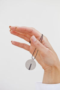 Close-up of hand holding key against white background