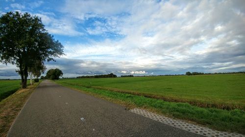 Road amidst field against sky