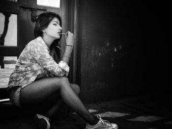 Young woman looking away while sitting on wall