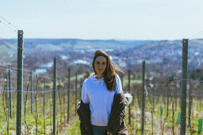 Young woman standing on field against sky