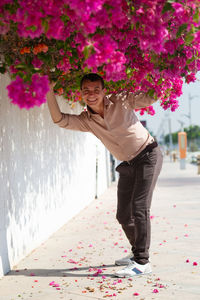 Portrait of young woman with pink flowers against plants