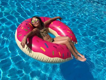 High angle view of smiling girl on inflatable ring floating at swimming pool