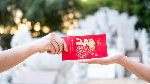 Cropped hand giving new year greeting card to woman