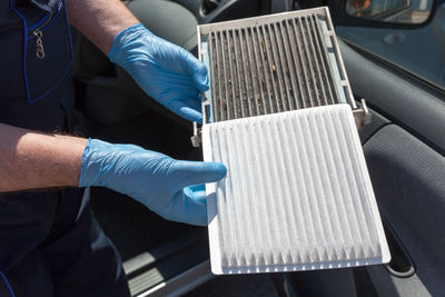 Midsection of man holding car filter