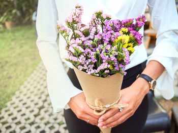 Midsection of businesswoman holding bouquet outdoors