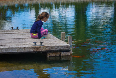 Full length of woman sitting on pier over lake