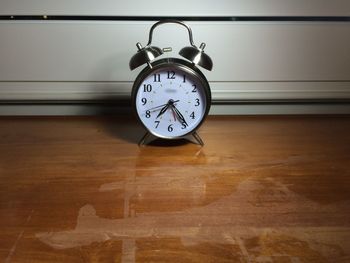 Alarm clock on wet hardwood floor at home