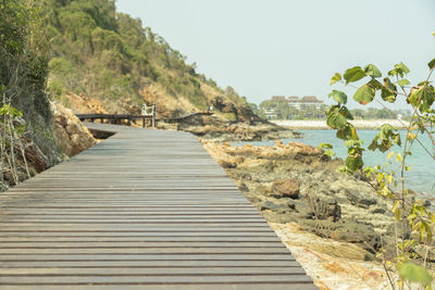 Boardwalk leading towards sea against sky