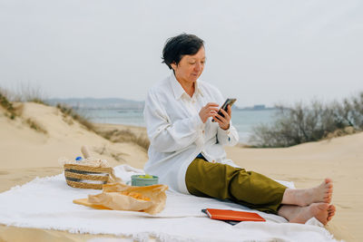 Adult woman on the beach in spring, summer orders online products for a picnic. purchase. fast