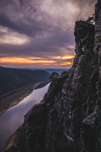 Rock formation by sea against sky during sunset