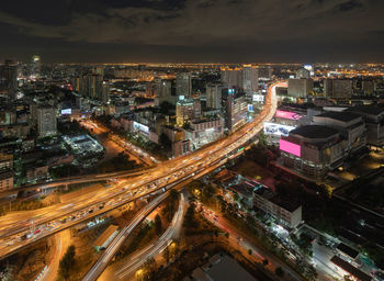 High angle view of illuminated street amidst buildings in city at night