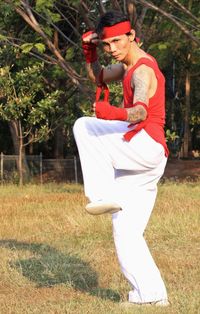 Side view of young woman holding umbrella on field