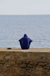 Rear view of man looking at sea against sky