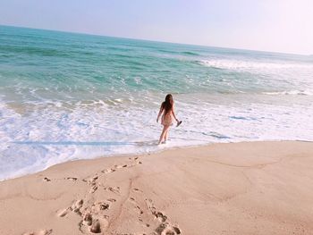 Rear view of woman walking at beach