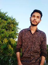 Portrait of young man standing against clear sky