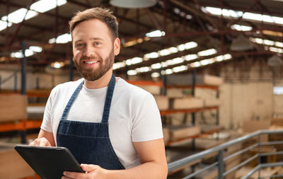 Portrait of young man using mobile phone while standing in cafe