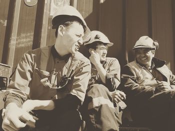 Smiling manual workers sitting against wall