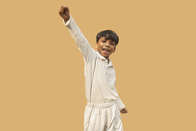 Portrait of happy boy standing against gray background