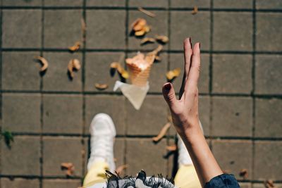 Directly above shot of ice cream cone falling from woman hand