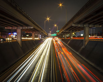 Light trails on road in city against sky at night