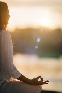 Sungazing. woman meditating by the lake, sitting in lotus position.