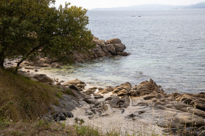 Scenic view of rocks by sea against sky