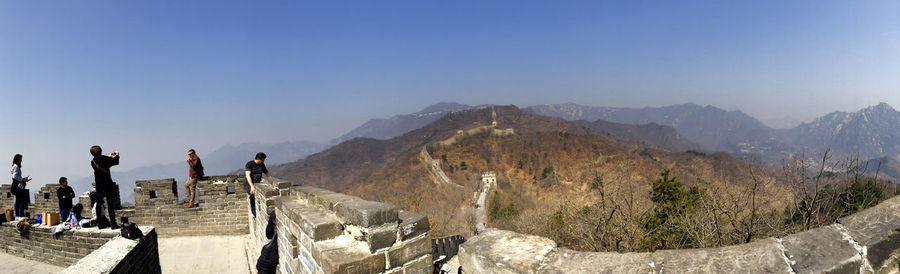 People standing on great wall of china against clear blue sky