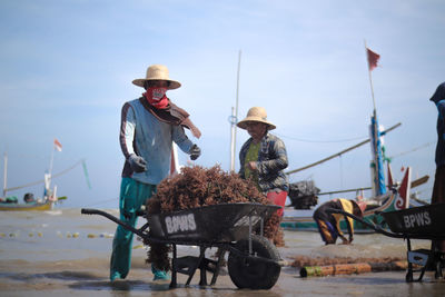 People working on boat against sky