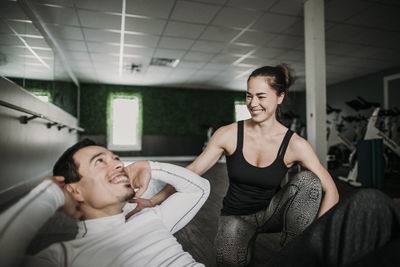 Female personal trainer laughs with her male client while he works out