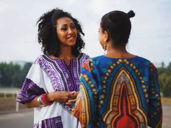 Young female friends standing at race course against sky