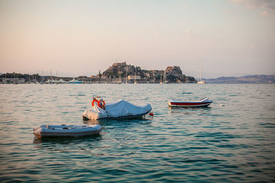 Boats moored in sea against buildings in city