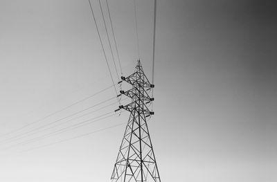 Low angle view of electricity pylon against clear sky