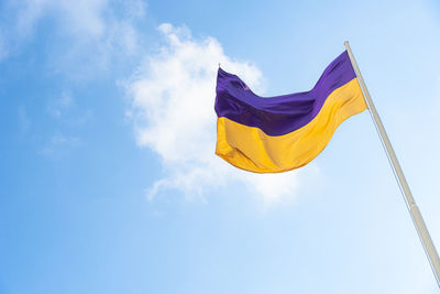 Low angle view of flag against blue sky