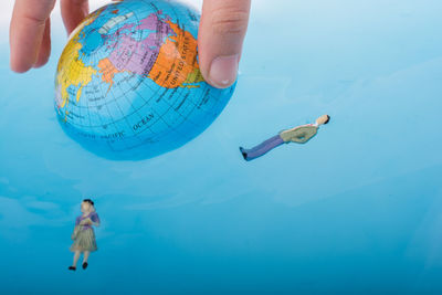 Close-up of hand holding globe by toys floating on water