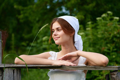 Portrait of young woman standing against trees