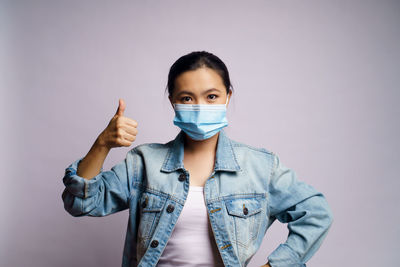 Portrait of young woman standing gesturing against gray background