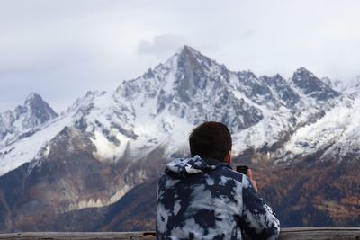 Rear view of man on snowcapped mountain against sky
