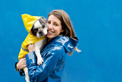 Woman with dog standing against wall