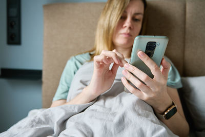 Midsection of woman using mobile phone on bed at home