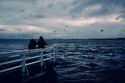 Couple on the pier watching a stormy sea