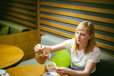 Close-up of woman pouring drink in cup at restaurant