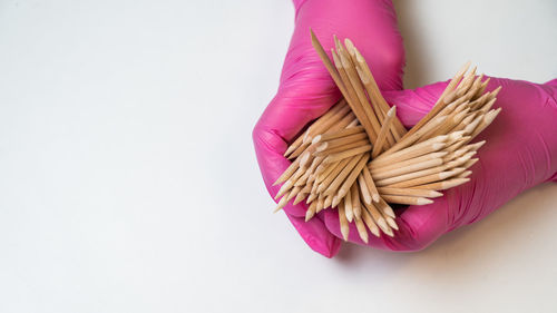 Cropped hand of person holding rope against white background