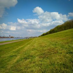 Scenic view of grassy field against cloudy sky