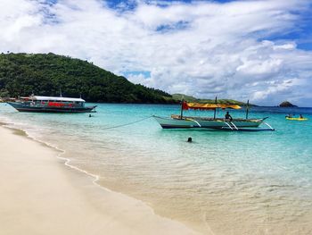 Boats in sea against cloudy sky