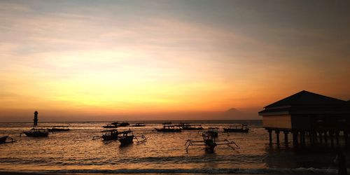 Silhouette people on beach against sky during sunset