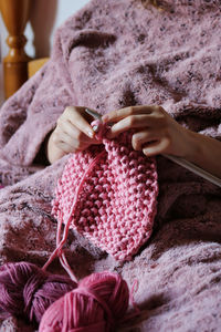 Female hands knitting pink cotton yarn