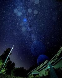 Low angle view of trees against star field