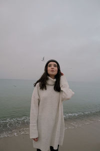 Portrait of woman standing at beach against sky