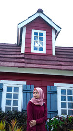 Portrait of woman standing against building