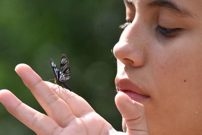 Close-up of girl holding butterfly outdoors